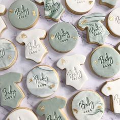 baby shower cookies decorated with blue and white icing on a marble countertop, including ones that say it's a boy