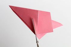 a pink origami bird with scissors sticking out of it's back end