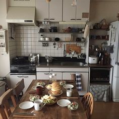 a kitchen table with plates and cups on it in front of the stove top oven