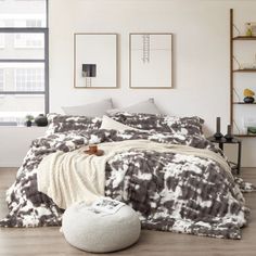 a bedroom with a bed covered in a black and white blanket next to a window