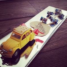 a yellow toy truck on top of a wooden table next to a sign that says happy birthday