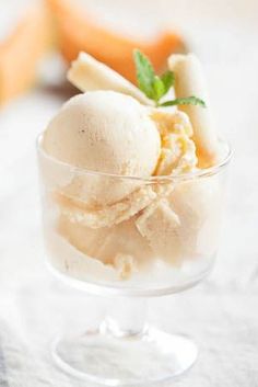 two scoops of ice cream sit in a glass bowl on a white tablecloth