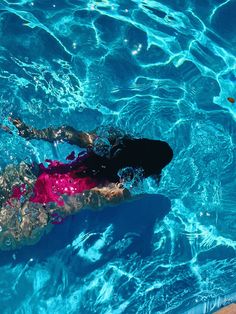 a person swimming in a pool with blue water