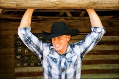 a man wearing a cowboy hat is holding up a piece of wood above his head