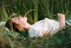 a woman laying in the grass with her eyes closed