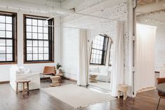 a living room filled with furniture and windows next to a wooden floor covered in white curtains