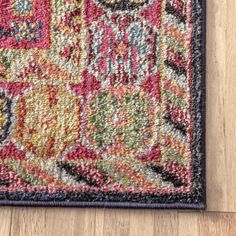 a multicolored area rug on a wooden floor with a black border around it