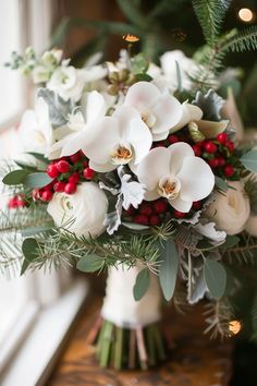 a bouquet of flowers sitting on top of a wooden table next to a christmas tree