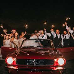 a group of people holding sparklers in front of a car