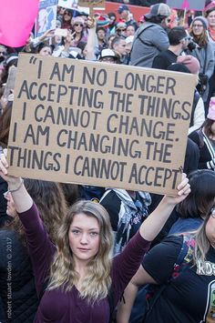 a woman holding up a sign in front of a crowd