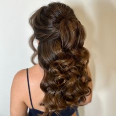 the back of a woman's head with long, curly hair in half - up style