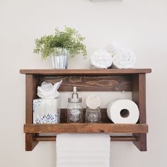 the shelf above the toilet is filled with towels and other bathroom items, including rolls of toilet paper