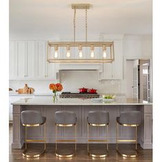 a kitchen island with three stools and an island in the middle is surrounded by white cabinets