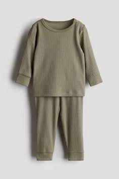 Set with a shirt and pants in soft  ribbed cotton jersey. Shirt with concealed snap fastener on one shoulder (sizes 2–4Y without snap fastener) and long sleeves with ribbed cuffs. Pants with covered elastic at waistband and ribbed hems. Plain Long Sleeve Loungewear Sets, Casual Ribbed Sets For Fall, Ribbed Loungewear Sets For Winter, Ribbed Long Sleeve Loungewear Sets, Stretch Ribbed Winter Set, Ribbed Stretch Sets For Winter, Plain Cotton Long Sleeve Sets, Ribbed Stretch Winter Sets, Winter Ribbed Loungewear Sets