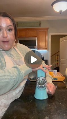 a woman holding a blue blender on top of a kitchen counter