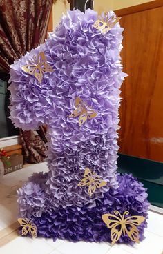 a purple cake with gold butterflies on it's top and the number one made out of paper