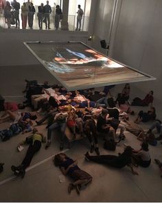 a group of people laying on the ground in front of a large screen with images