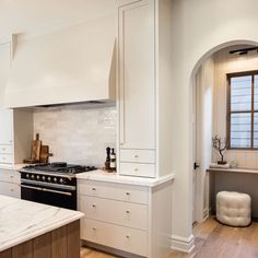 a kitchen with white cabinets and an island in the middle is shown, along with a marble countertop