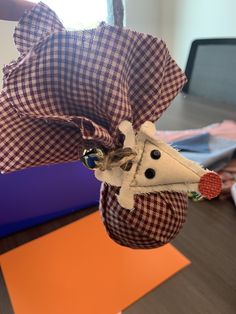 a stuffed animal hanging from the side of a table with a laptop in the background