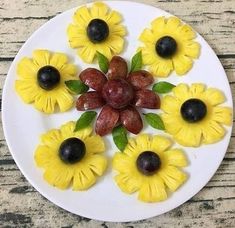 a white plate topped with yellow flowers and black olives