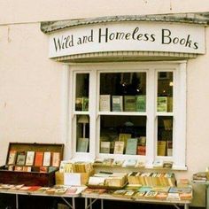 a table with books on it in front of a window and sign that says wild and homeless books