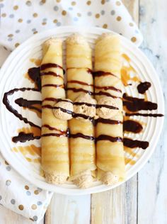 a white plate topped with crepes covered in chocolate