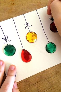 someone is making an ornament for christmas tree ornaments with colored stones and string