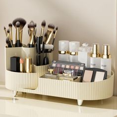 a white tray with makeup and brushes in it sitting on a counter next to a mirror