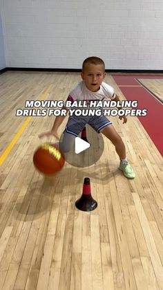 a young boy holding a basketball on top of a wooden floor