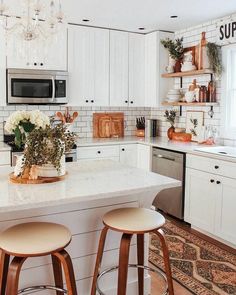 a white kitchen with two stools and a center island that has flowers on it