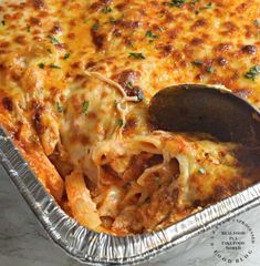 a casserole dish with meat and cheese being lifted from the pan by a spatula