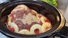 a crock pot filled with meat and fruit