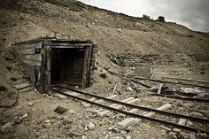 an old outhouse sitting on the side of a hill with railroad tracks running through it