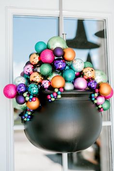 a large pot filled with lots of different colored balls and decorations on top of a window sill