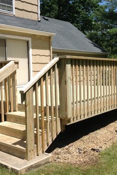 a wooden porch with steps leading up to the door and side of a house on a sunny day