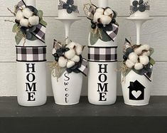 three white vases with black and white decorations on top of a shelf next to each other