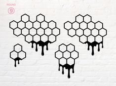 three honeycombs with dripping black paint against a white brick wall