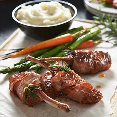 some meat and vegetables on a plate with mashed potatoes, asparagus and carrots