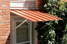 an orange awning over a window in front of a red brick building with white windows