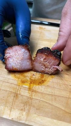 a person in blue gloves cutting up some meat