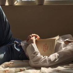 a person sitting on a bed reading a book