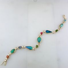 Ethiopian opals, topaz, tanzanite, citrine, peridot, tourmaline, green diopsite of various shapes and sizes are each delicately set in handmade bezels. This 14k yellow gold bracelet has been hand signed by the artist. 14K Yellow Gold & 22K Yellow Gold Ethiopian opals, topaz, tanzanite, citrine, peridot, tourmaline, green diopsite 7 1/4" long Plunger Clasp with figure 8 safety 9mm at widest point Weighs approximately 8.4 grams Hand Signed Available for Order. (Orders Placed today will ship in Bezel Set Diamond, Figure 8, Yellow Gold Bracelet, Bezel Setting, Ethiopian Opal, Citrine, Turquoise Bracelet, Tourmaline, Topaz