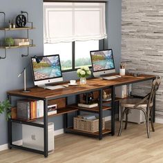 two computer monitors sitting on top of a wooden desk in front of a wall with shelves