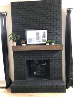 a black brick fireplace with potted plants on the mantle and a framed photo above it