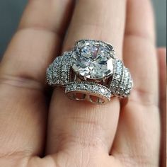 a close up of a person's hand holding an engagement ring and wedding band