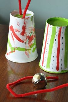 two tin canisters sitting on top of a wooden table next to a bell