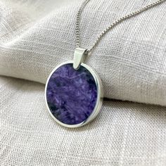 Charoite in a circular sterling silver pendant. This backless design allows both sides of the stone to be viewed. It won't matter which way the stone rests. This purchase comes with a 45cm sterling silver curb chain. Sterling Silver Medallion Necklace With Polished Finish, Sterling Silver Hallmarked Round Pendant Necklace, Minimalist Round Jewelry With Large Stone, Sterling Silver Large Round Pendant Jewelry, Silver Circle Gemstone Jewelry, Purple Necklace With Large Round Pendant, Purple Sterling Silver Necklace With Polished Finish, Sterling Silver Necklace With Large Circular Pendant, Sterling Silver Jewelry With Large Stone