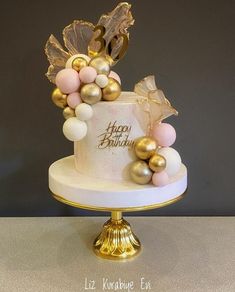 a white and gold birthday cake with balloons on top