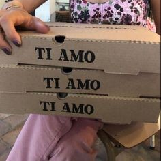 a woman sitting on a chair holding a cardboard box with the words it amo ti amo