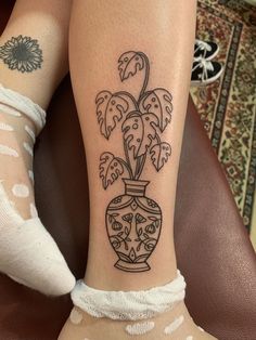 a woman with a tattoo on her leg has a flower in a vase tattooed on her arm